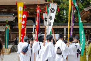 Boys wearing traditional costumes carry the Kumano flags
