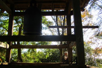 A man takes a rest under a bell at a shrine along the hike