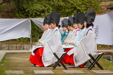 Young women from a historic coming-of-age ceremony in the adjacent garden teahouse sit in attendance