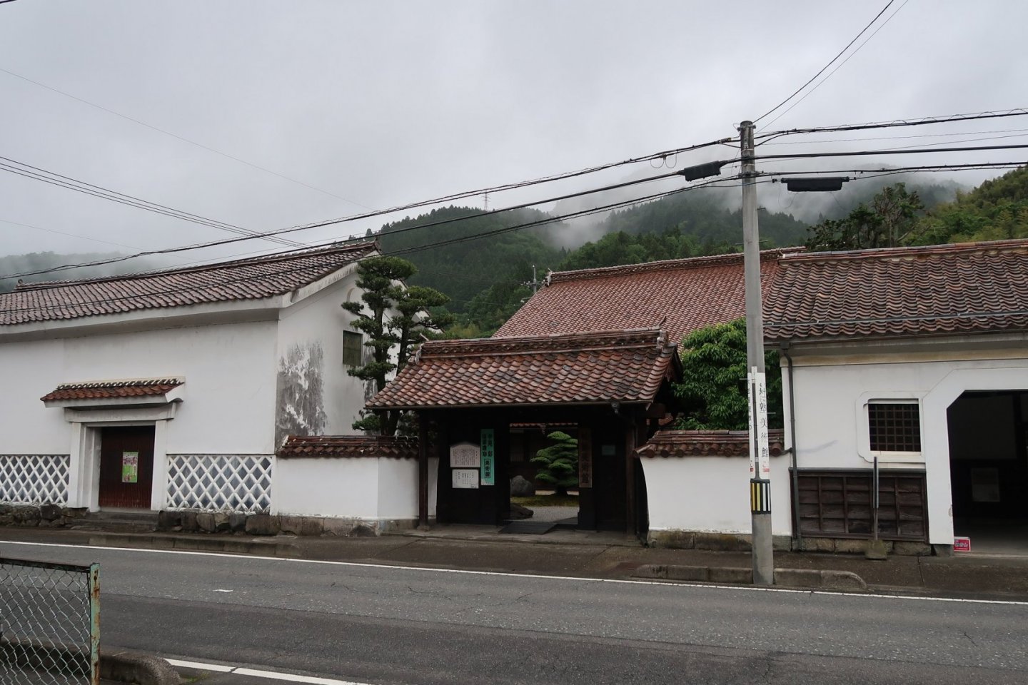 The front gate of the Morijuku Art Gallery with some rice granaries on either side of the gate