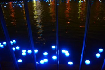 Lights passing by the edge of the river.