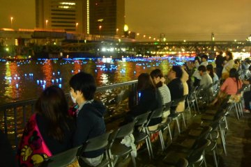 Relaxed visitors sitting along the banks of the Sumida RIver.