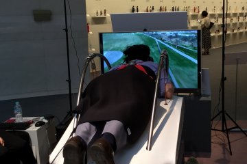A visitor enjoys a flight simulator in a gallery exhibit
