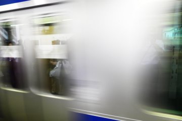 A JR Joban Line train departing from Kita Senju station in Tokyo. It was only later that I realised there was a reflection in the window of a person holding a bag.