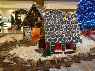 Life size gingerbread house surrounded by a marshmallow pebble, all technically edible. The gingerbread smells deliciously sweet and spicey.