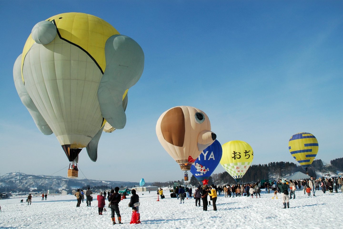 The snowy white landscape is filled with brightly colored balloons