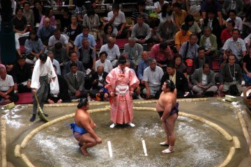 A pair of rikishi wrestlers and the gyoji referee between them.