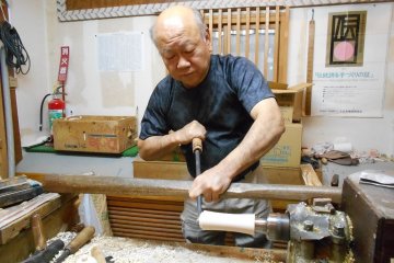 Artisan making a kokeshi doll