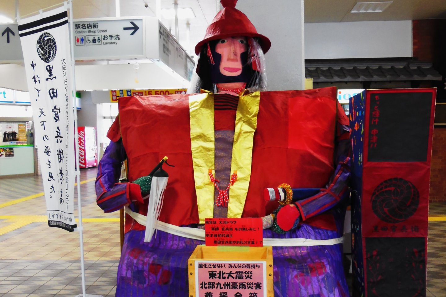 A Kanbeh Kuroda doll holding a donation box for the 3.11 earthquake