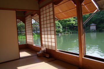The house has many open rooms looking out onto a pond