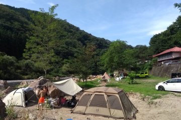 Camping on the riverside beach with the guesthouse in the background