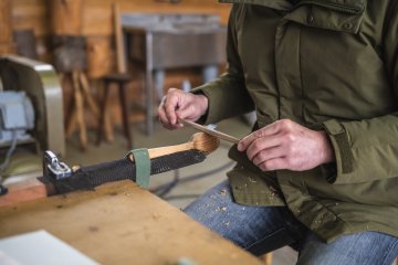 Using a special carving tool to prepare a wooden spoon at the Kubota Woodworking Shop