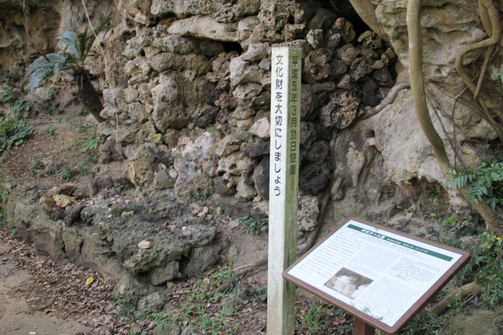 Một tấm bảng nhỏ viết bằng tiếng Anh và tiếng Nhật bên cạnh ngôi mộ, cung cấp thông tin chi tiết về tầm quan trọng của khu di tích