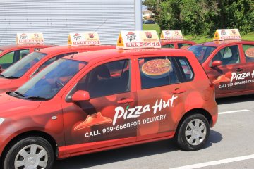 <p>Pizza Hut vehicles on Kadena Air Base in Okinawa are driven by and deliver food prepared by bilingual contract workers</p>