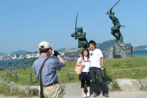 銅像前で記念写真を撮るカップル